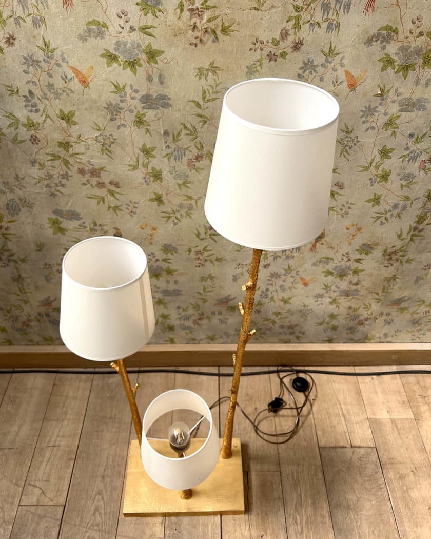Un lampadaire en métal martelé doré à trois bras de lumière